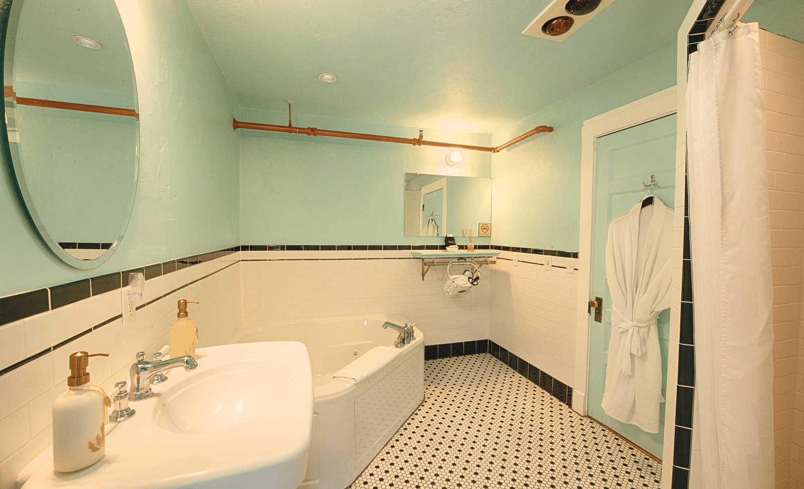 full view image of the bathroom with a wash basin along with a bathtub and a bathrobe hanging behind the door of the bathroom - Historic Tapoco Lodge