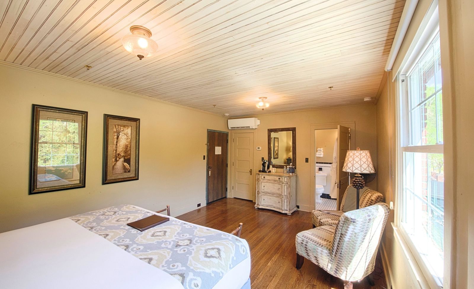 corner view of a cozy bedroom featuring a comfortable double bed with two decorative wall mounted frames - Historic Tapoco Lodge