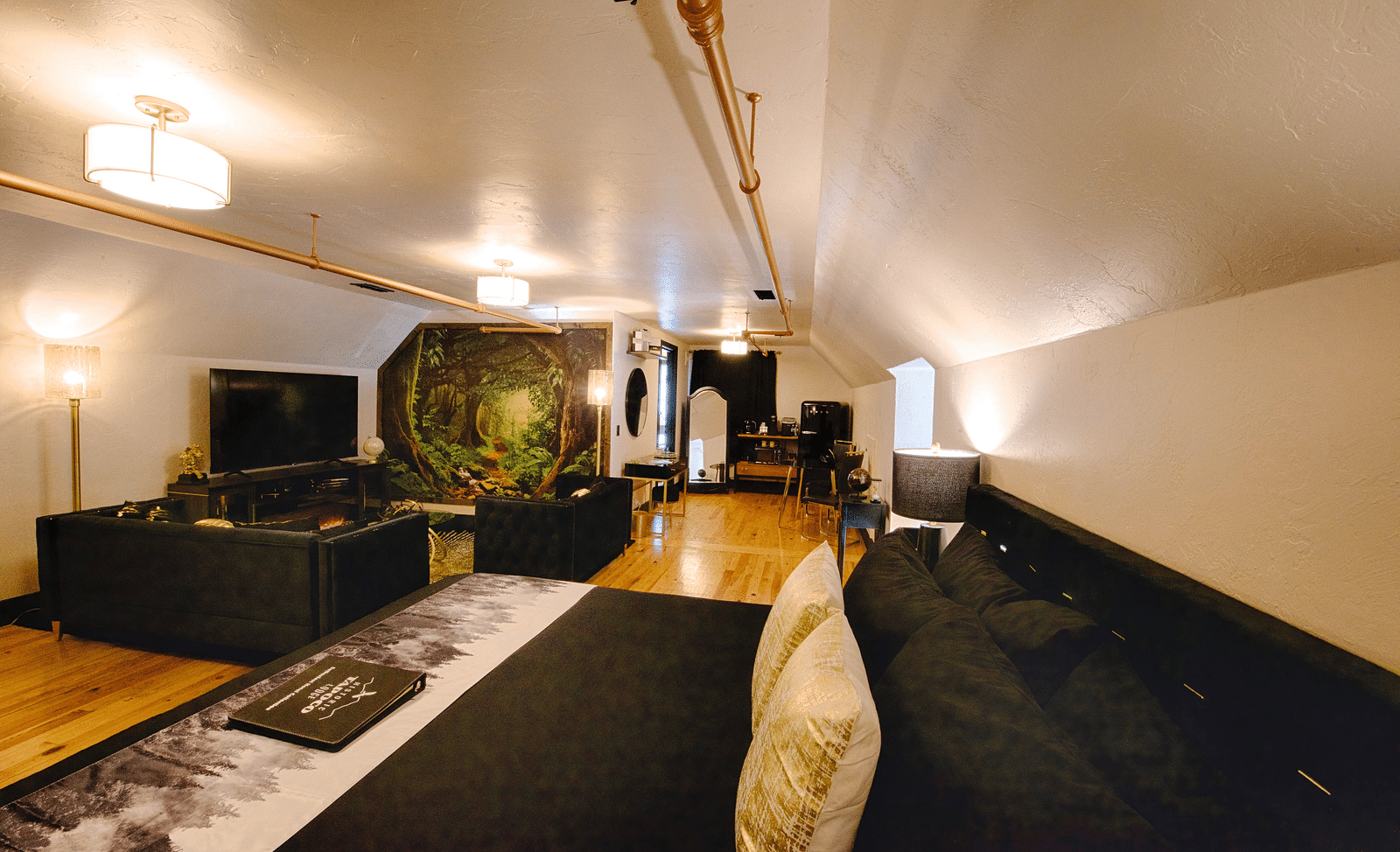 a suite with black linen spread over the double bed with a common seating area and a full screen television - Historic Tapoco Lodge