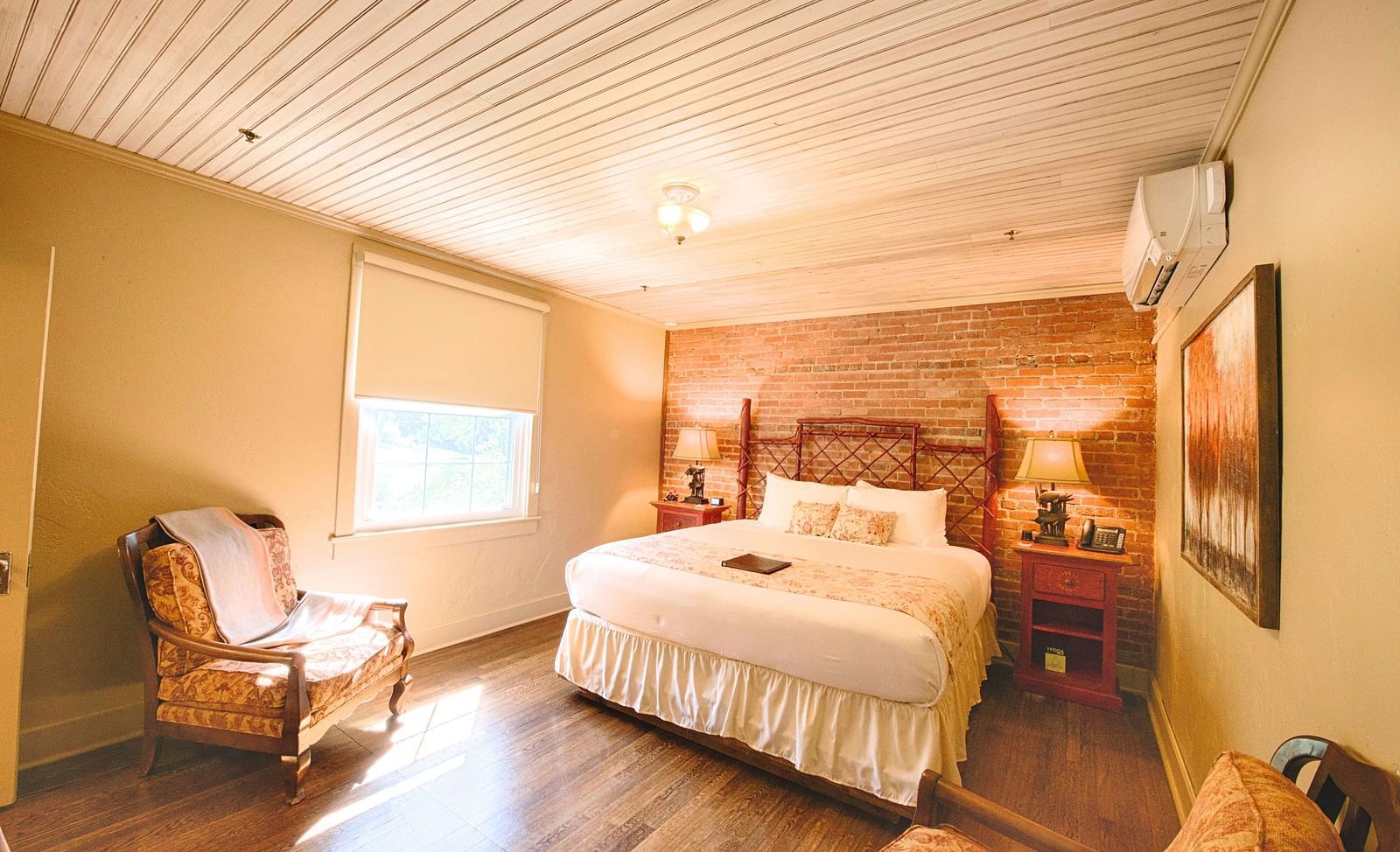 full view image of a bedroom featuring a bricked wall behind the double bed - Historic Tapoco Lodge