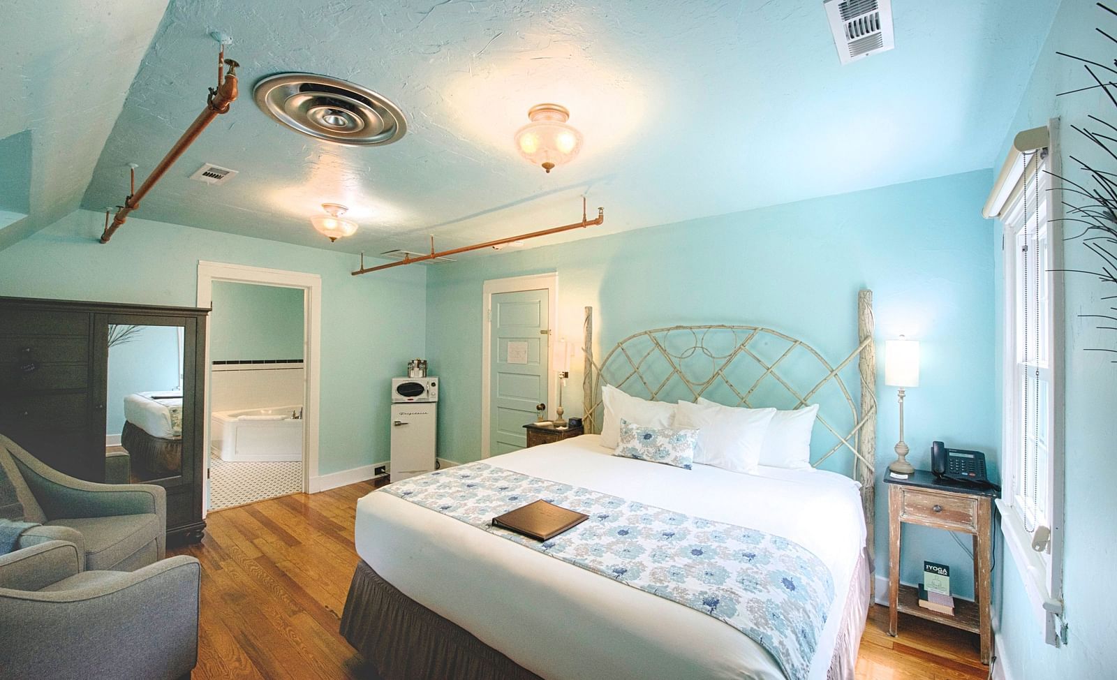 corner view image of the bedroom featuring a comfortable double bed with a window right by the bedside - Historic Tapoco Lodge