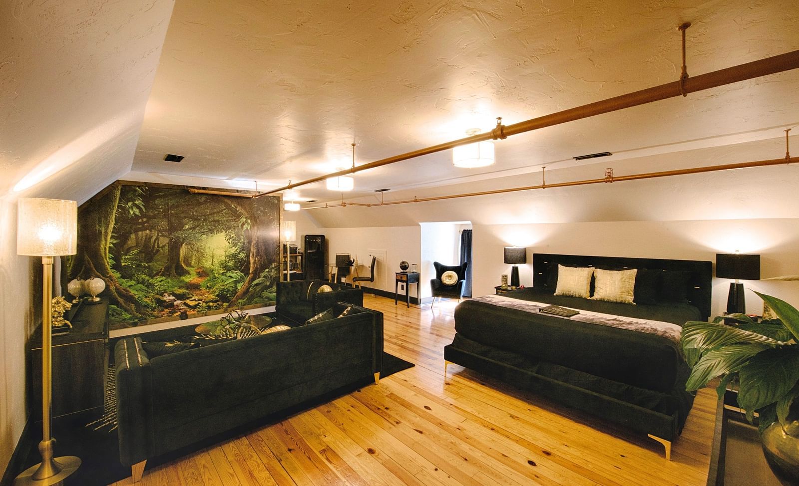 a spacious bedroom with a cozy double bed and black couch set in the common seating area with a jungle mastiff made in the feature wall of the suite - Historic Tapoco Lodge