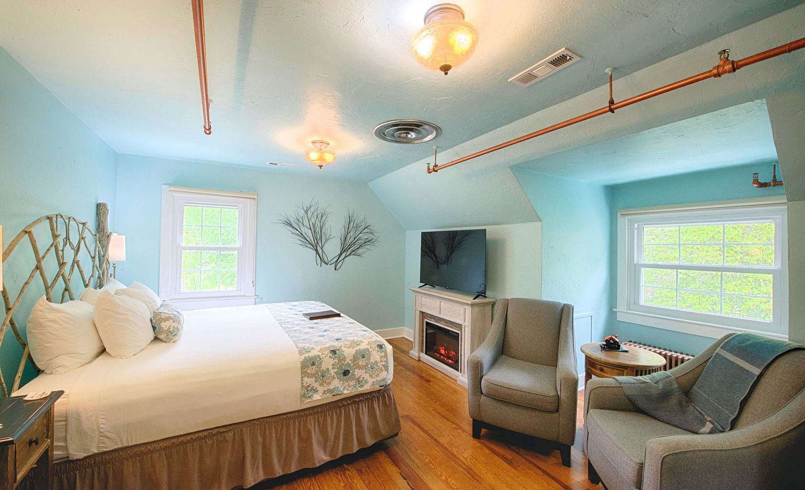 full view image of the laurel suite with pastel blue colored walls along with a flat screen television right opposite to the double bed - Historic Tapoco Lodge