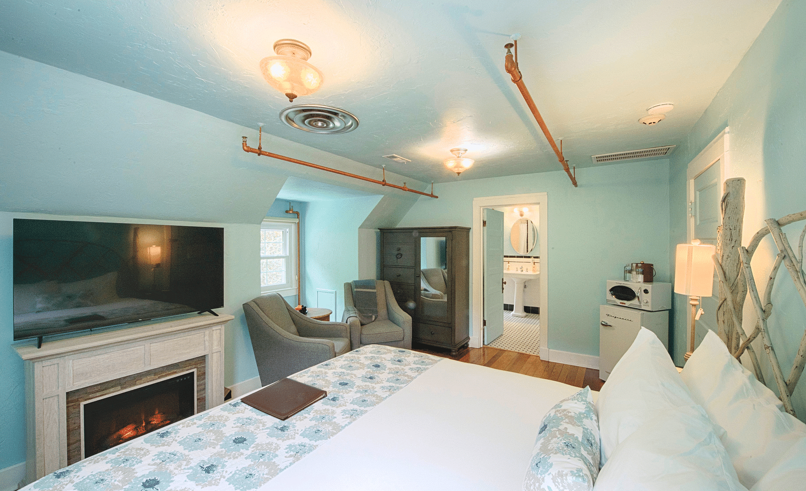 a room featuring an electric fireplace along with a flat screen television above it placed right opposite the bed - Historic Tapoco Lodge