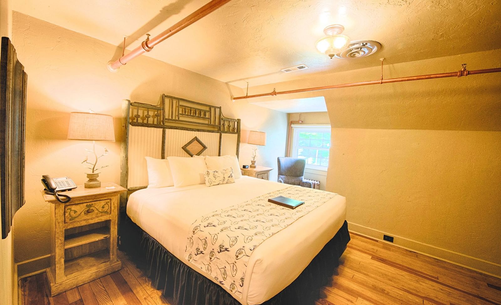 a comfortable double bed with a huge head board behind it in a warmly illuminated room - Historic Tapoco Lodge