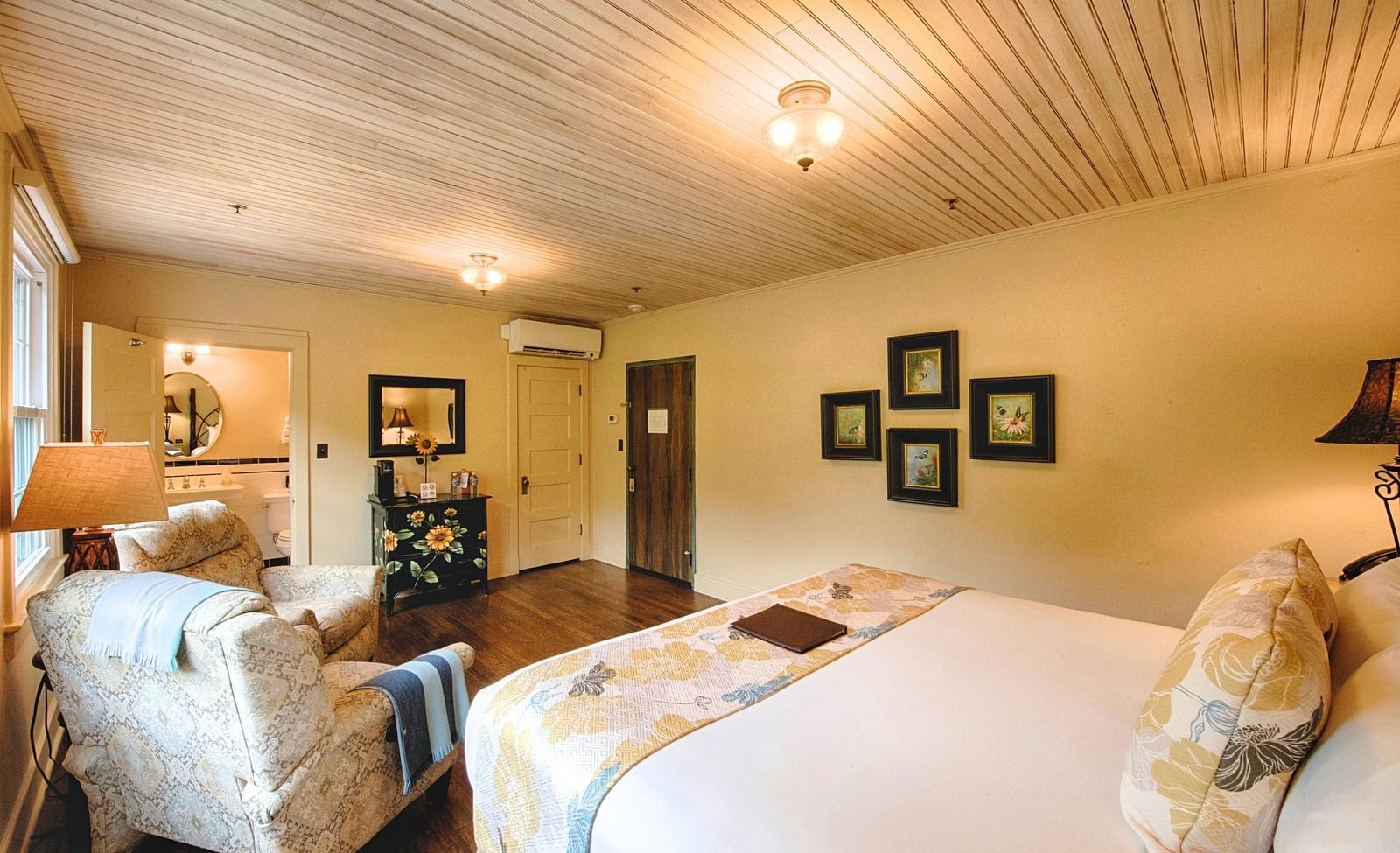 a cozy bedroom with minimalist and sleek interiors featuring a double bed and the back of a cushioned armchair - Historic Tapoco Lodge