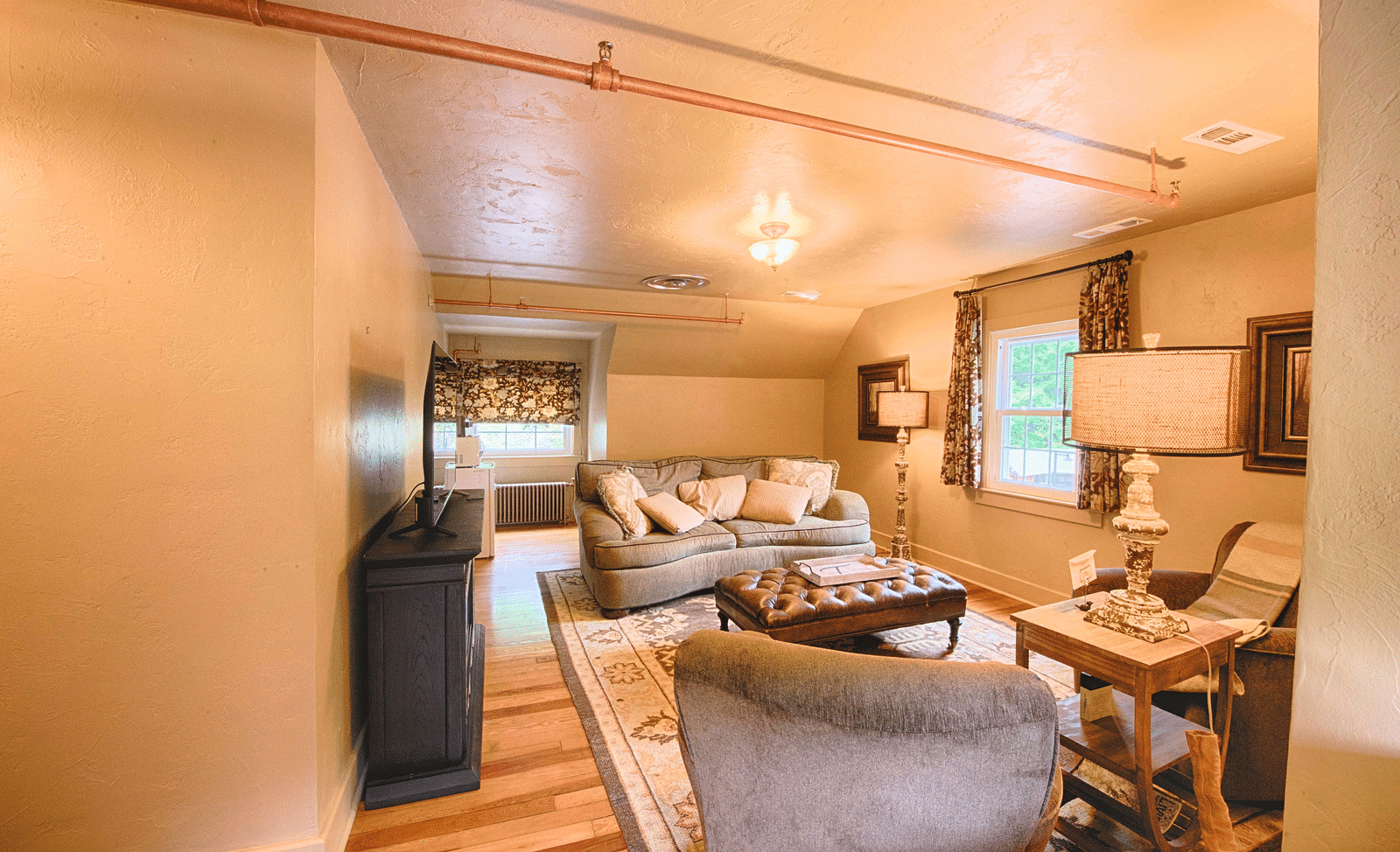 a spacious living room featuring a plush couch and two arm chairs in front of it - Historic Tapoco Lodge