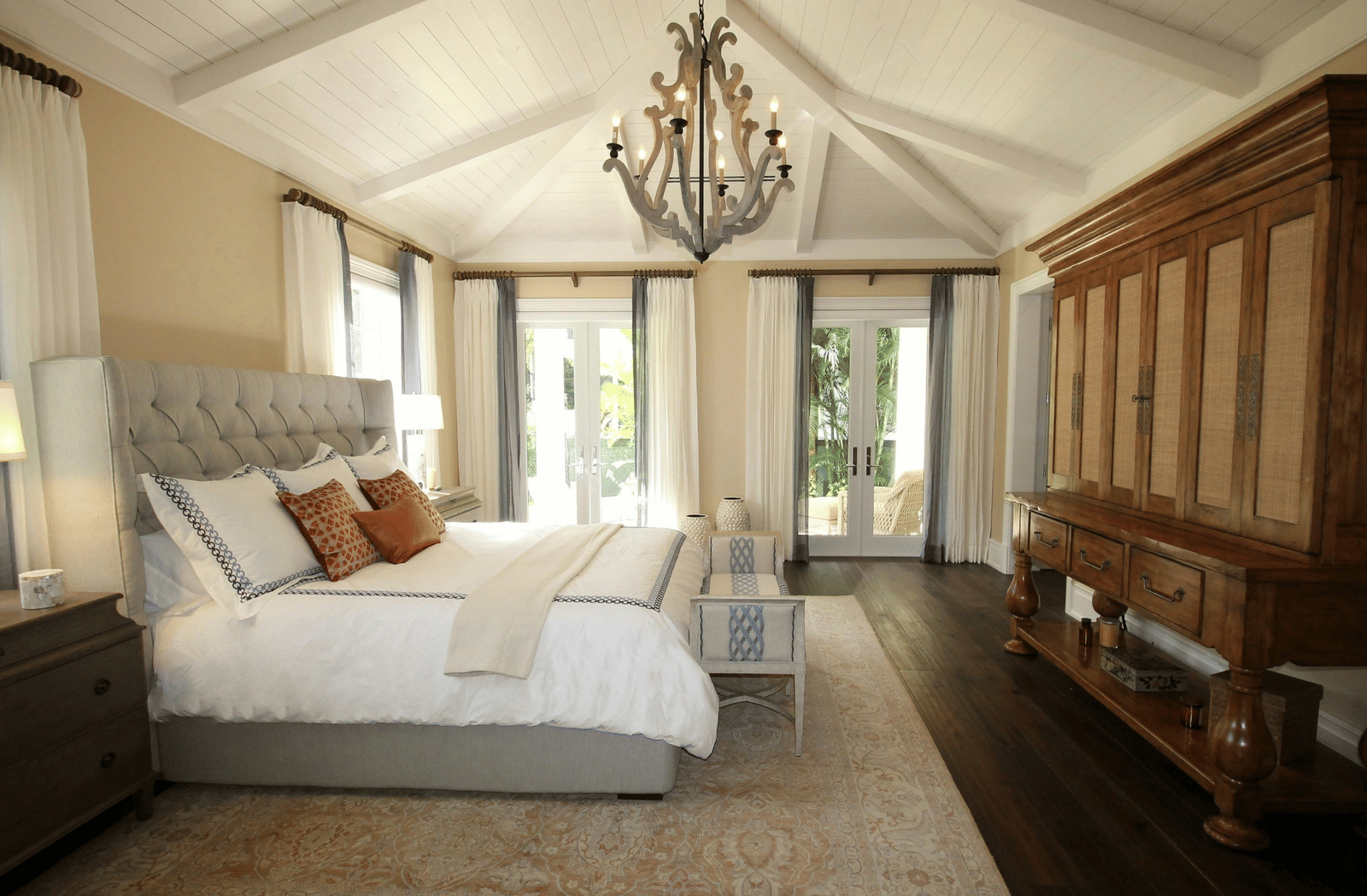 Side view image of the bed with a chandelier hanging over the double bed.