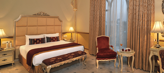 Image of a room with a bed and a chair on the side at Rajasthali Resort & Spa Jaipur.