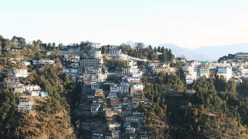 Scenic hillside settlement built along steep cliffs, overlooking a deep valley with clustered houses under a clear blue sky