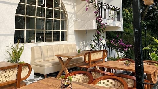 Outdoor dining area with wooden tables, wicker chairs, and pendant lights. - VITS Kunjham Retreat, Gangtok