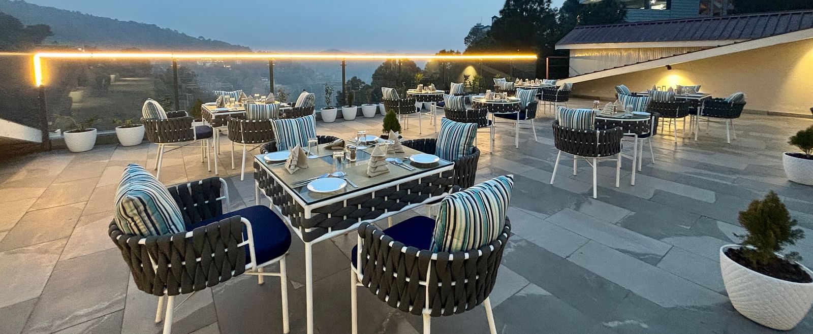 Outdoor dining area at twilight with neatly arranged tables and scenic views – ARNISA Boutique Hotel
