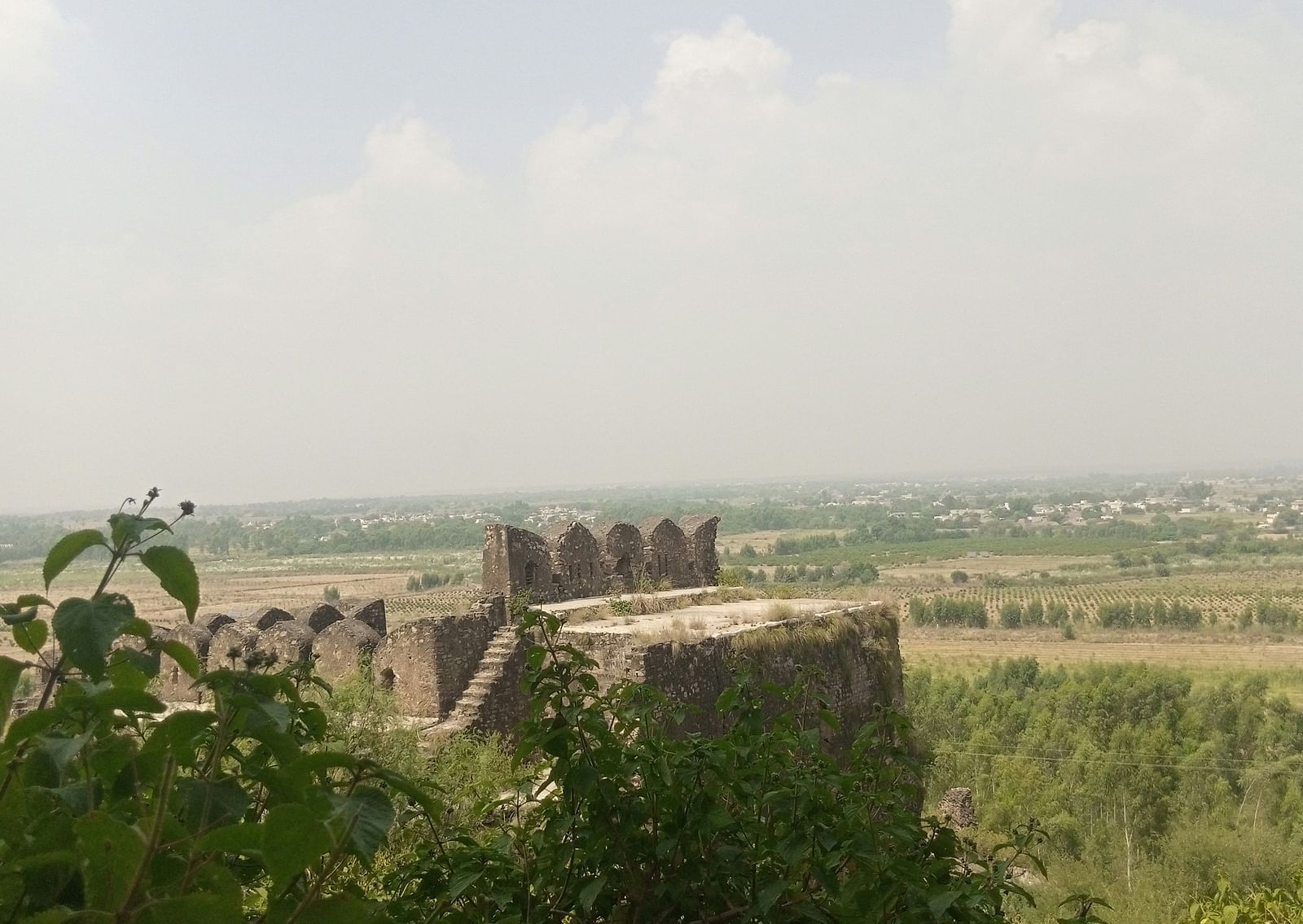 An overview of an ancient fort perched atop a hill with greenery all around it.