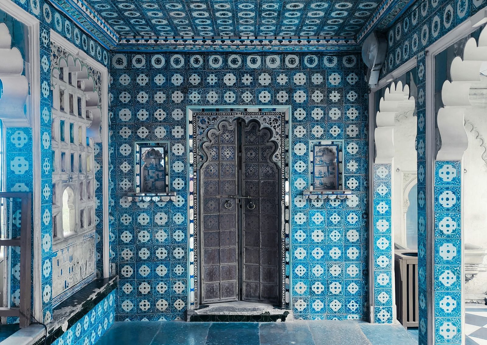 Interior of a palace room with blue tiled walls and patterned floor.