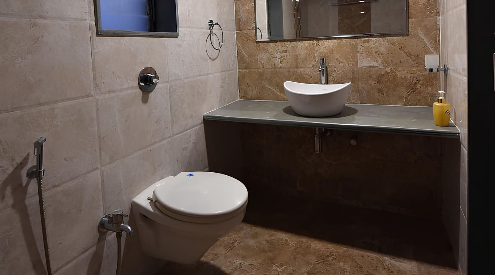 Bathroom of Deluxe Cottage at The Kanila Resort  with a toilet, sink, and vanity with brown cabinets and a marble counter top.