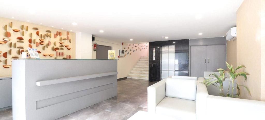 Full view of the recpetion area at Pravasa Stay, Ahmedabad (Alba Premier), with the front desk along with a common seating area in front of it.