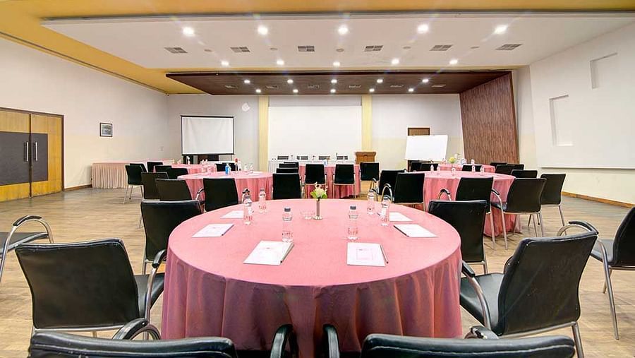 a banquet hall with cluster style seating and round tables - Camel Valley Resort, Igatpuri