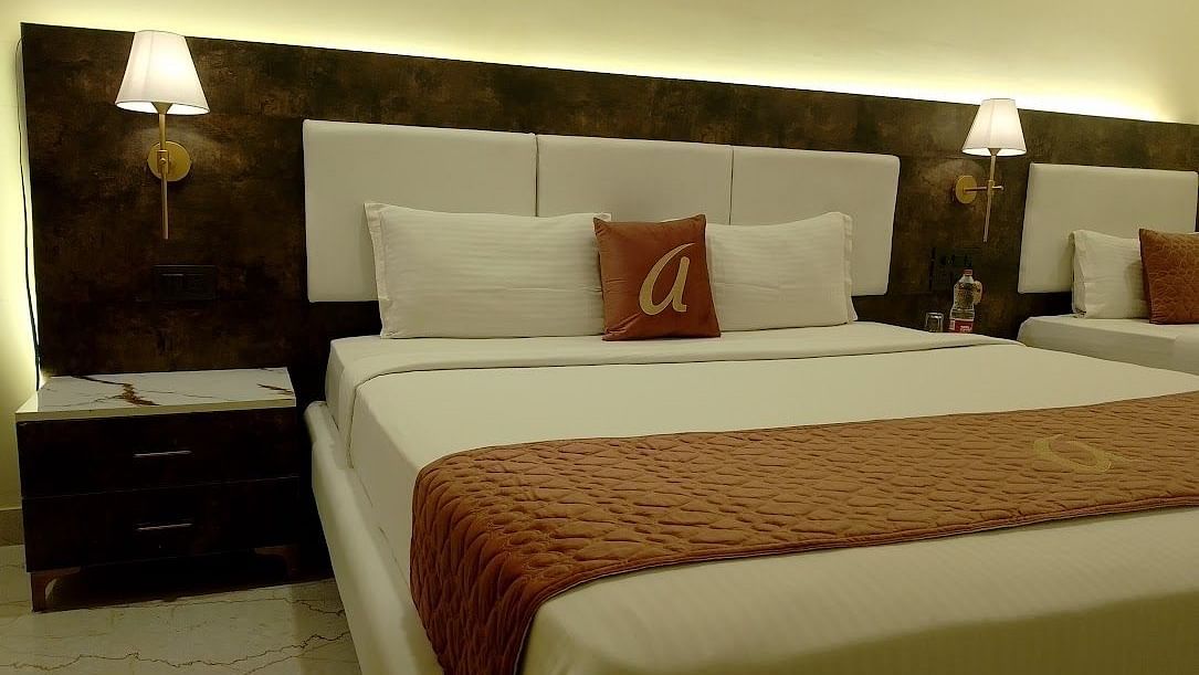 A luxurious hotel bedroom with a large double bed and another bed in the far side ,elegant bedside lamps, and a sophisticated dark brown and beige colour scheme - Astra Hotels and Suites, HSR Sector 7