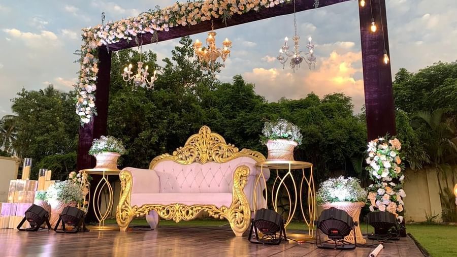 Decorated stage with golden sofa and floral canopy setup for a celebration at Ilara Hotels & Spa, OMR, Chennai