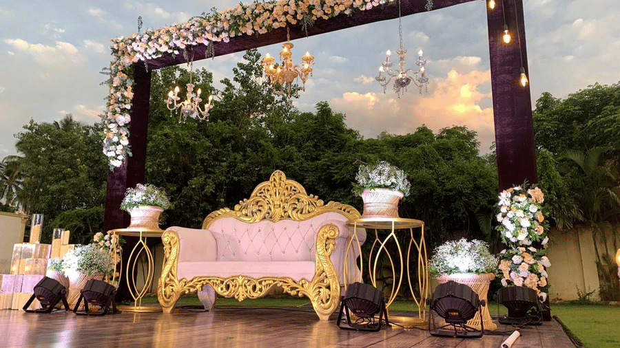 Decorated stage with golden sofa and floral canopy setup for a celebration at Ilara Hotels & Spa, OMR, Chennai