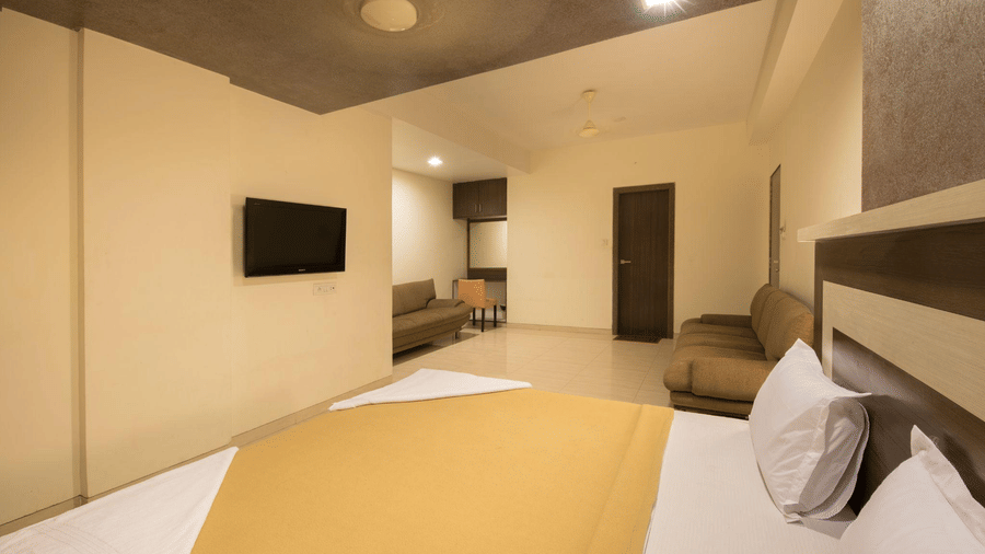 Wide-angle view of a hotel suite showing a large bed in the foreground and a sitting area further back.