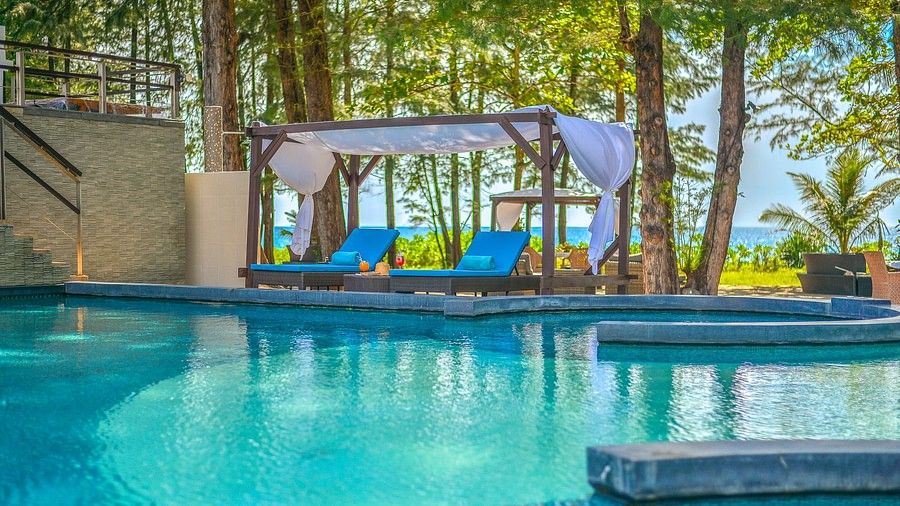 image highlight two sun loungers in a shed facing the swimming pool with lush green canopy in the background - Maikhao Dream Villa Resort & Spa, Phuket