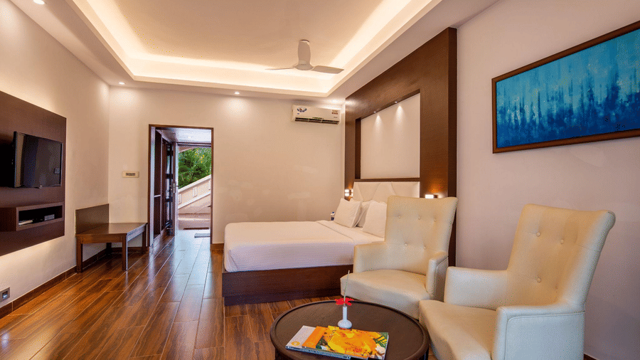 Deluxe room consist of big two arm chairs, TV, table and a painted art frame on the wall at Avana Resort