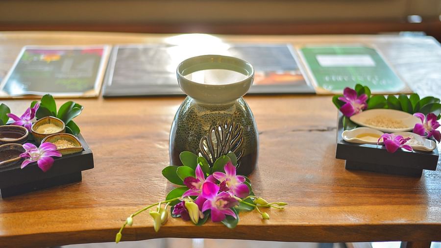 An oil diffuser lamp with flower petals in front of it, placed carefully and aesthetically on a wooden table - Maikhao Dream Villa Resort & Spa, Phuket
