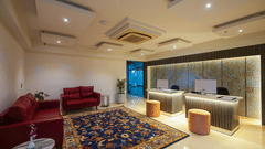 An image of the lobby with red couches and two reception desks with monitors - Grand Continent, Malleshwaram