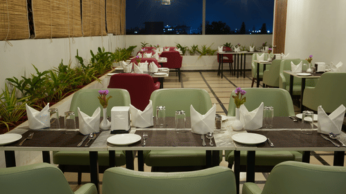 A view of our restaurant with green and red chairs around the tables - Grand Continent, Malleshwaram