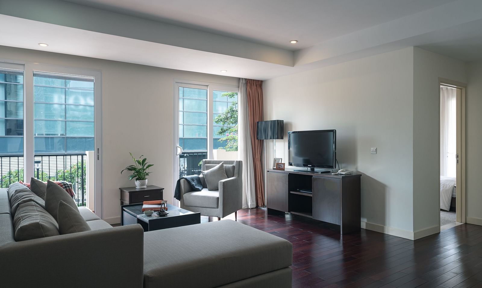 A living room with a sofa, a television, and large windows | Three-bedroom Suite | Central Mansions, Phnom Penh