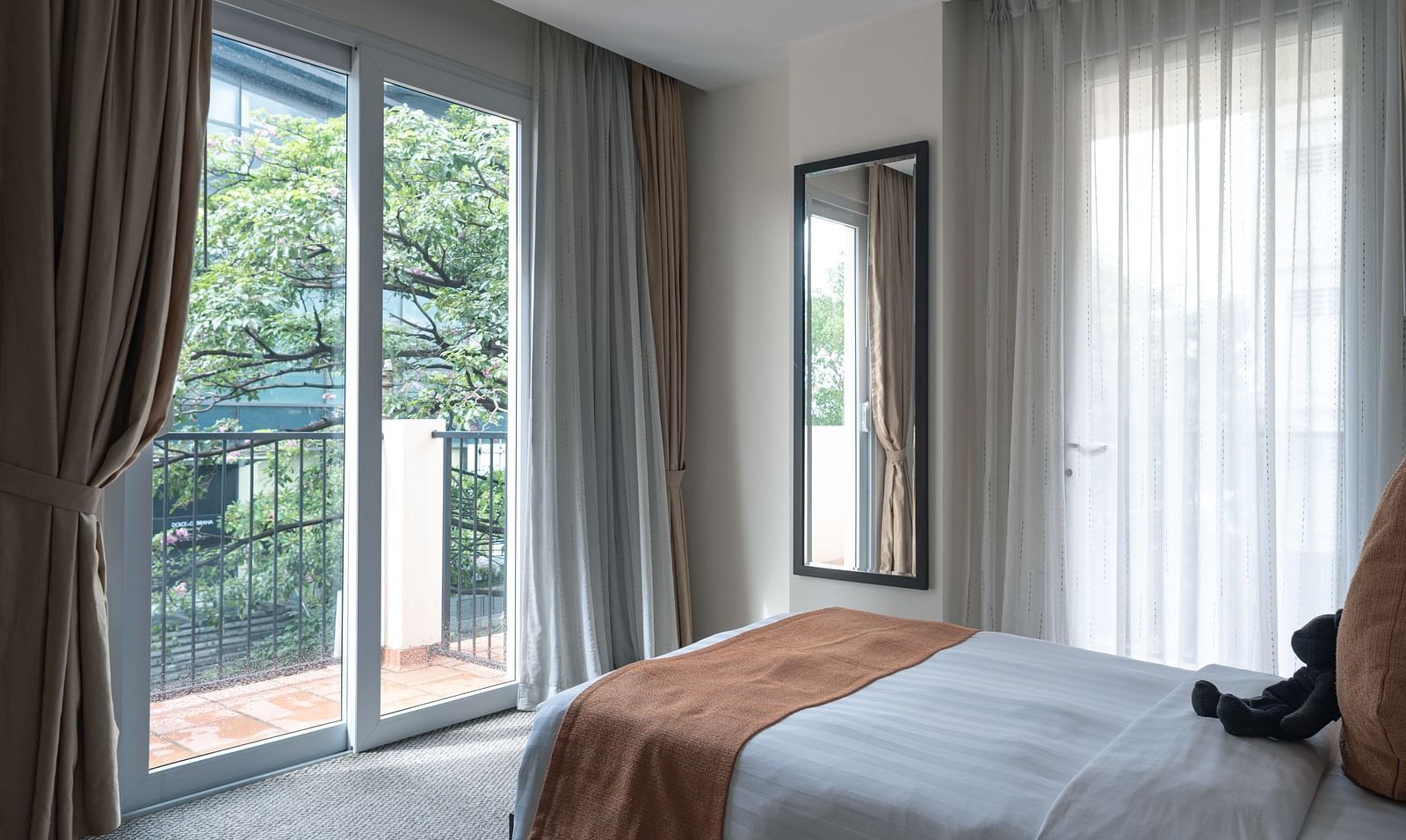 A bedroom with a bed, a window with curtains, and a balcony | Three-bedroom Suite | Central Mansions, Phnom Penh