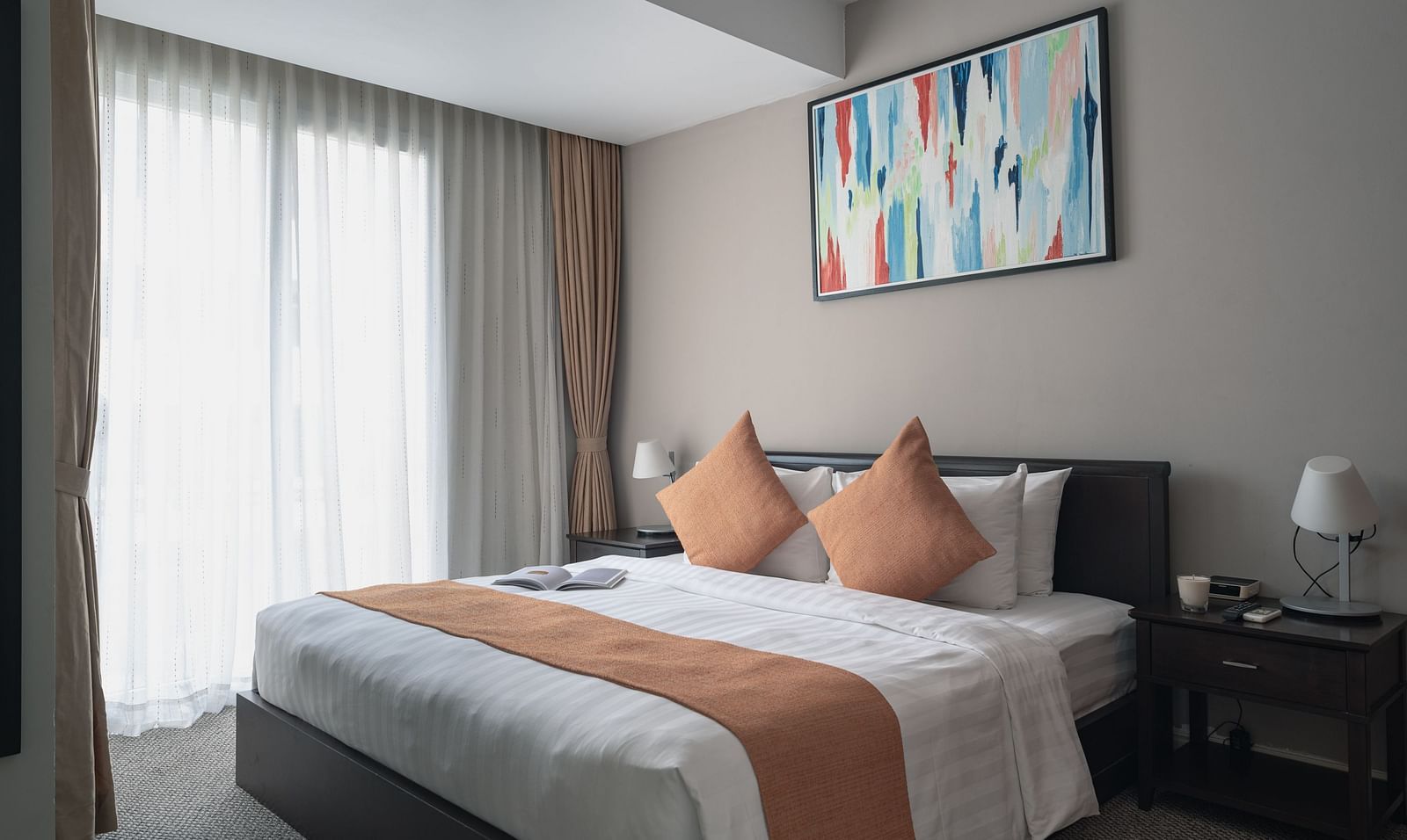 A bedroom with a large bed, a nightstand, and a piece of art on the wall | Three-bedroom Suite | Central Mansions, Phnom Penh