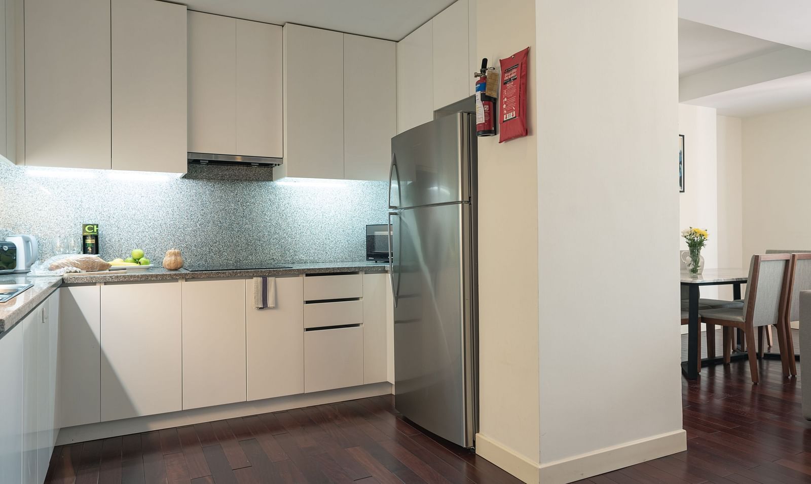 A kitchen with light-coloured cabinets, a refrigerator, and a dining area | Three-bedroom Suite | Central Mansions, Phnom Penh