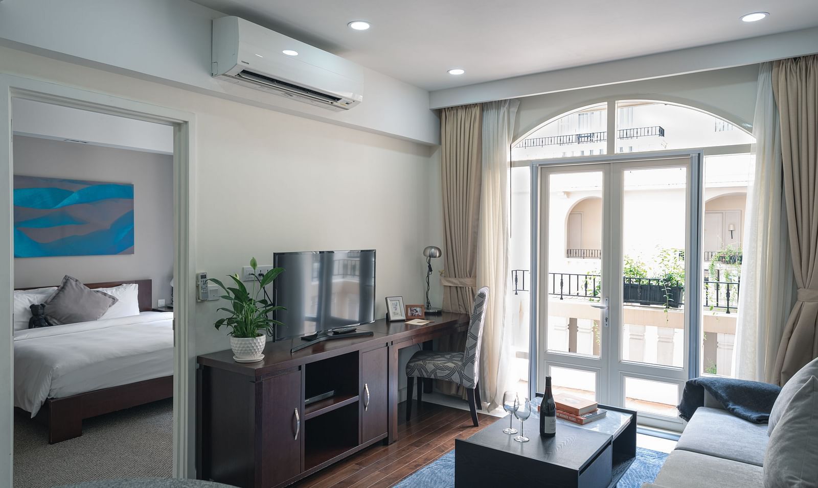 A living room with a grey sofa, a coffee table, and a television | Two-bedroom Suite | Central Mansions, Phnom Penh