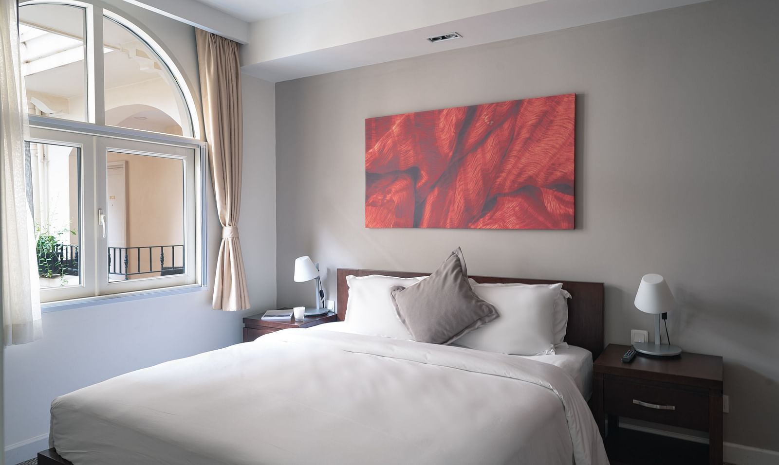 A bedroom with a large bed, a nightstand, and a piece of art on the wall | Two-bedroom Suite | Central Mansions, Phnom Penh