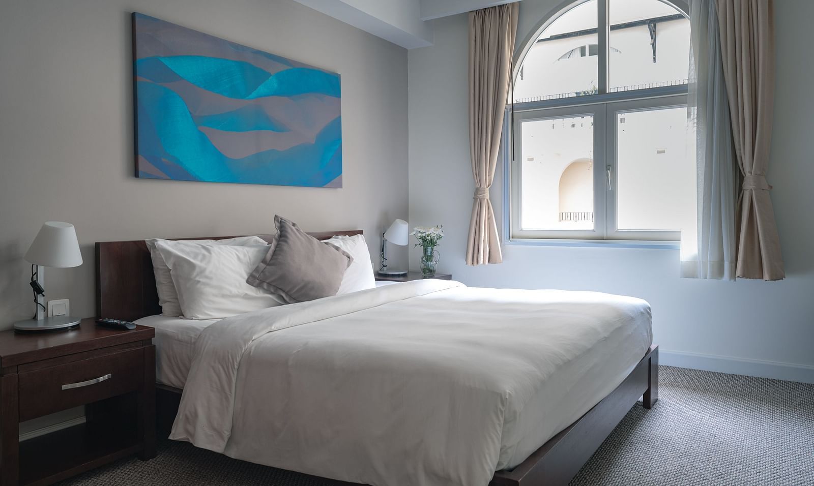 A bedroom with a large bed, a nightstand, and a painting on the wall | Two-bedroom Suite | Central Mansions, Phnom Penh