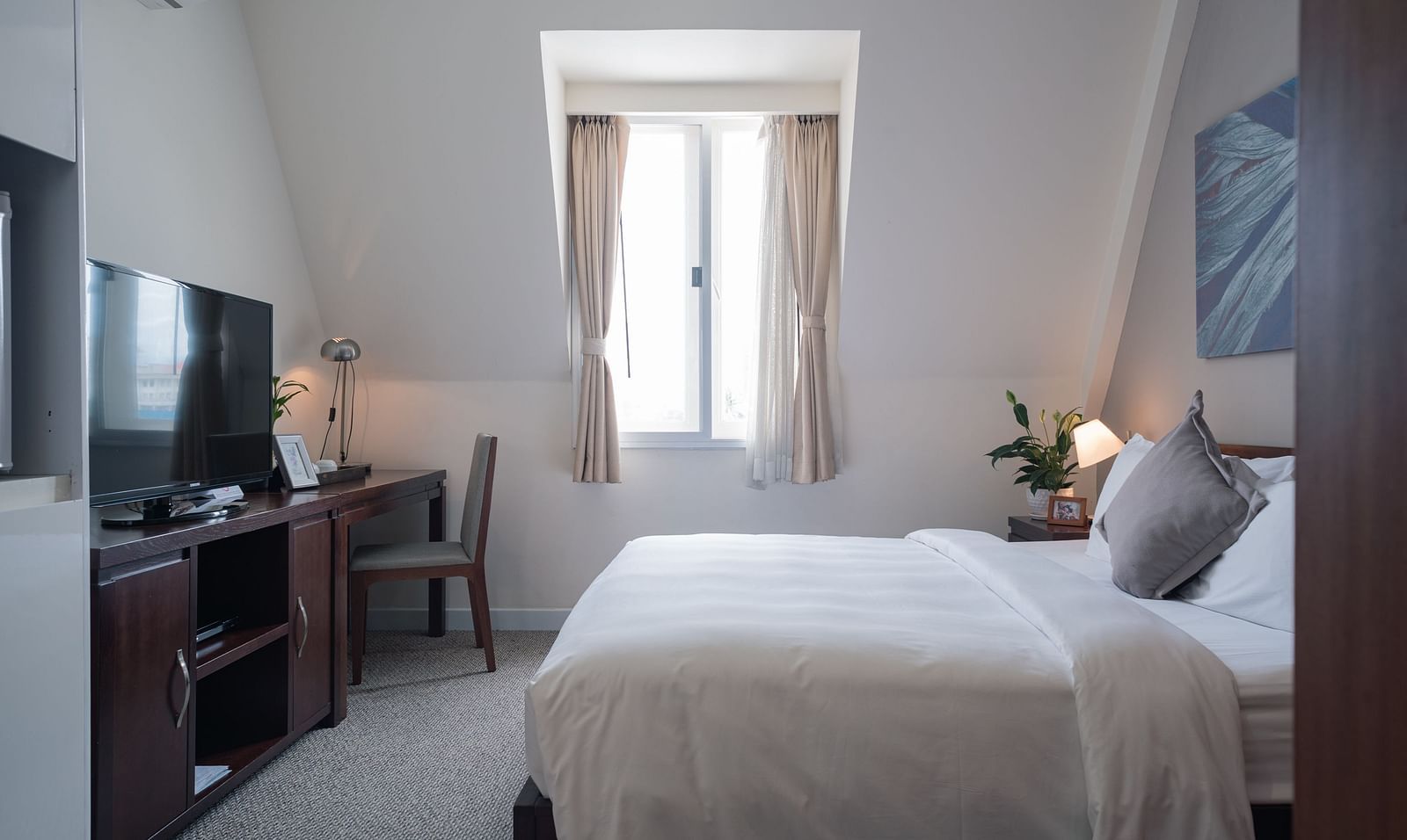 A bedroom with a bed, a desk, and a television | Studio | Central Mansions, Phnom Penh