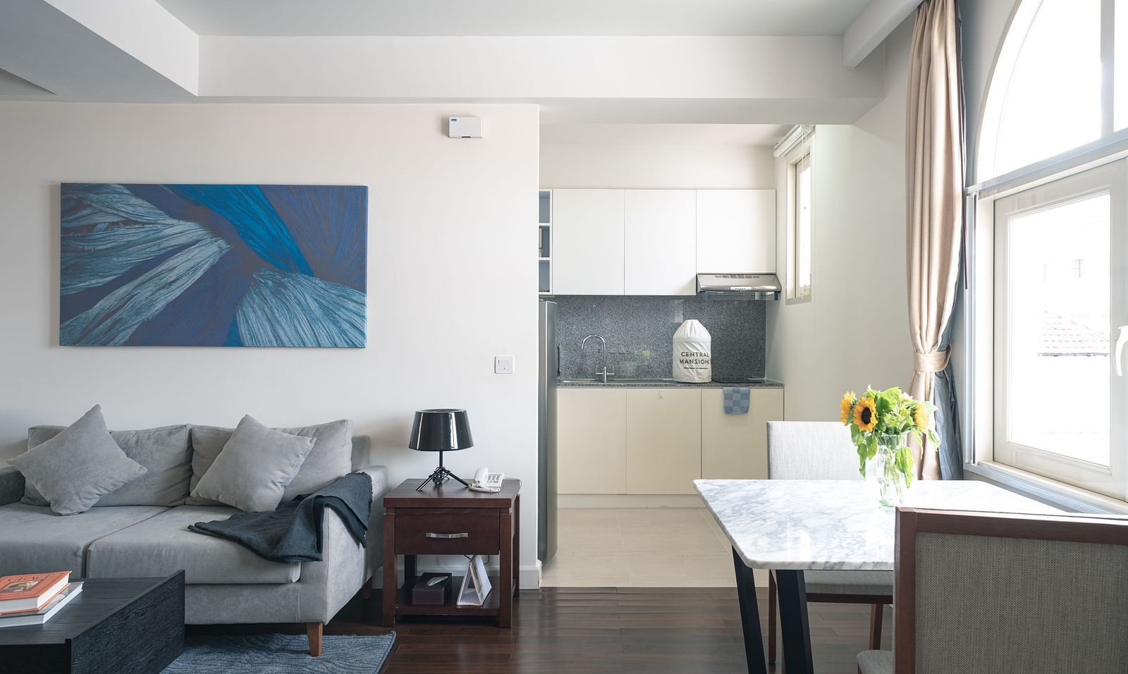 A living room with a sofa, a coffee table, and a small dining table with chairs | One-bedroom Suite | Central Mansions, Phnom Penh