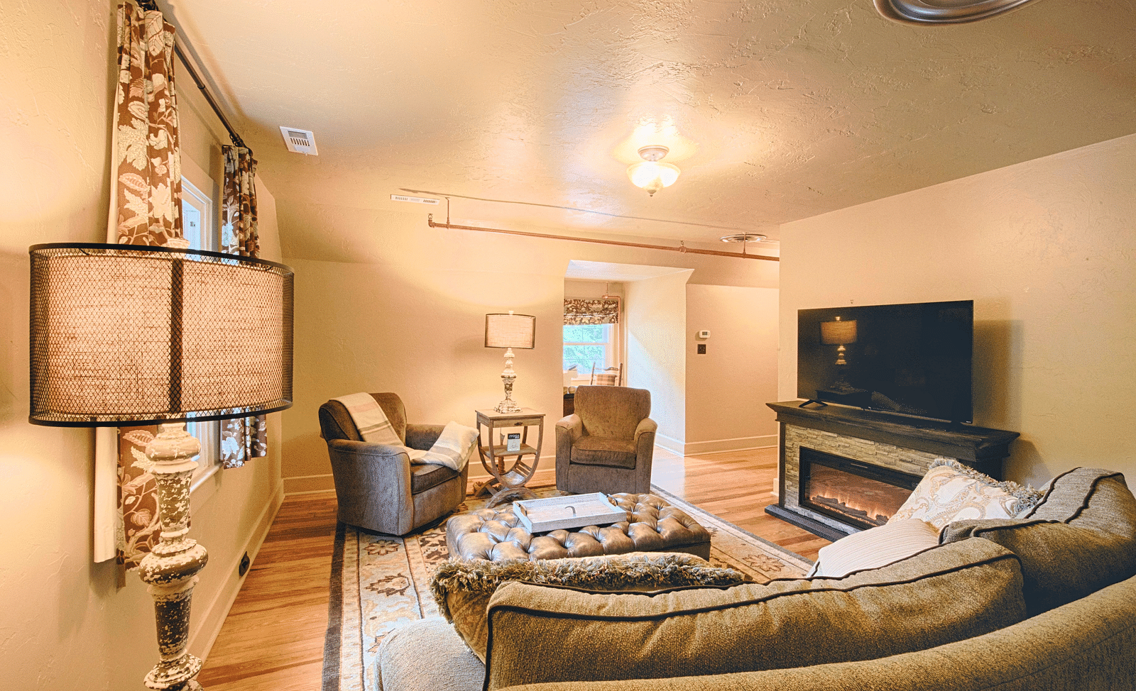 corner view image of the living room featuring a cozy seating area with an electric fire place and a flat screen television - Historic Tapoco Lodge