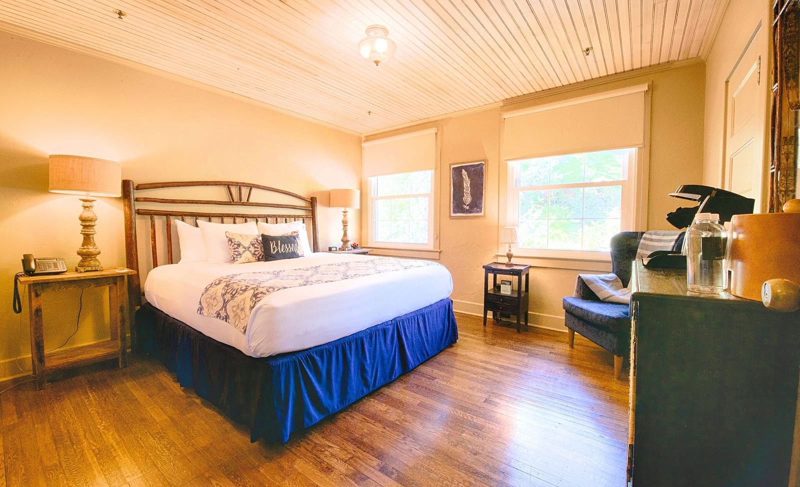 full view image of a room featuring a double bed with bed side tables along with a wooden cabinet in front of it - Historic Tapoco Lodge