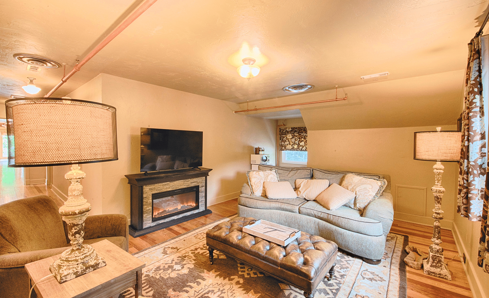 full view image of the living area with a soft couch adorned with a lot of cushions and a beautiful center piece - Historic Tapoco Lodge
