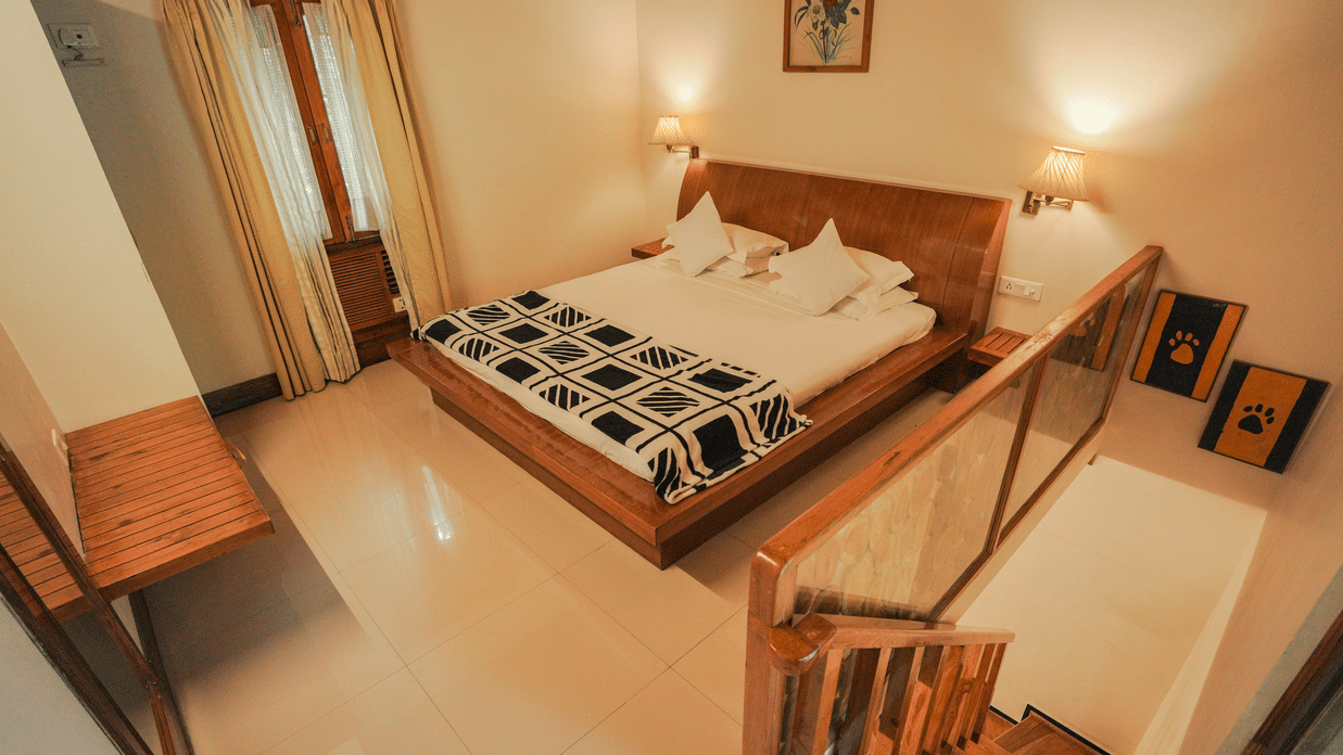 A bedroom with a bed, a chair, and a patterned rug, warm lighting - The Den Corbett Resort & Spa, Kumeria.