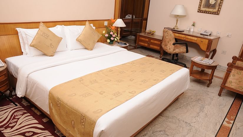 a double bed with side tables and a study table on the side inside one of the rooms - Raj Park Hotel, Chennai