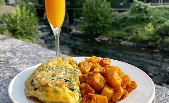 a fluffy omelette served with a glass of fresh orange juice besides the river - Historic Tapoco Lodge