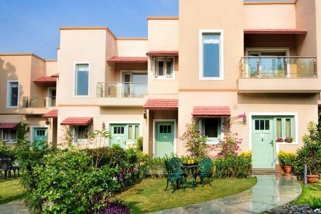 Row of peach-coloured two-storey villas with balconies and manicured front gardens at Karma Chalets.