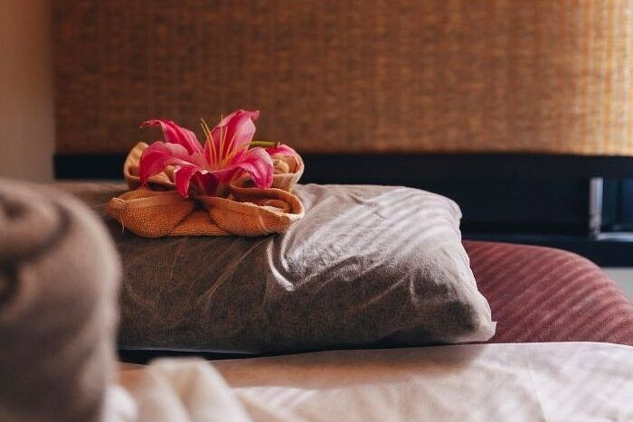 Bed with pillows and flower arrangement in a room at Karma Chalets.