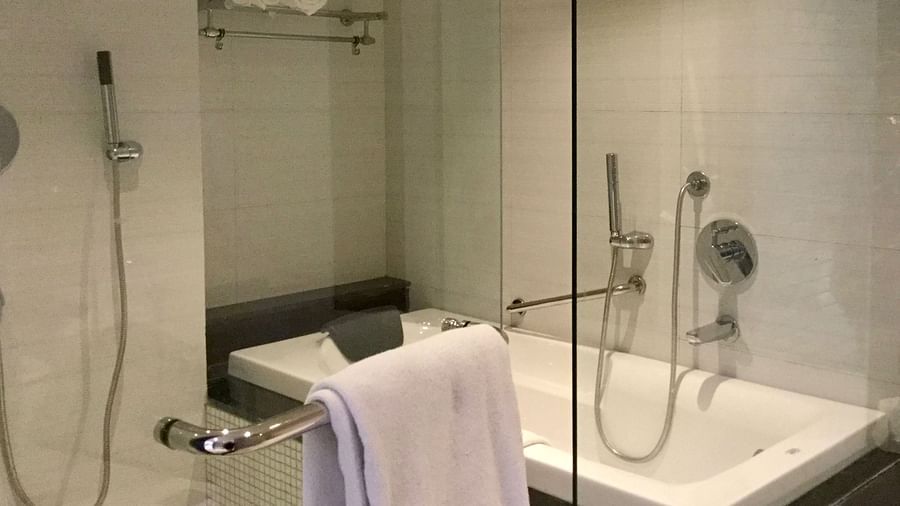 A full size bathtub in a bathroom separated by a glass door - Ramada by Wyndham, Ghaziabad, Vasundhara