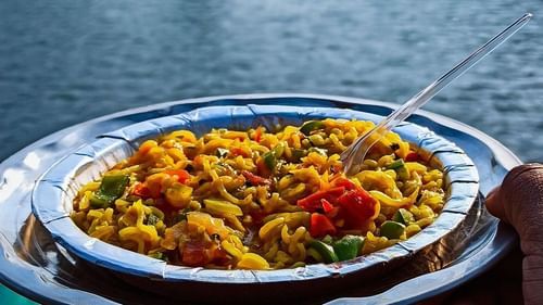 A person enjoying a bowl of maggi with a lake view amidst mountains