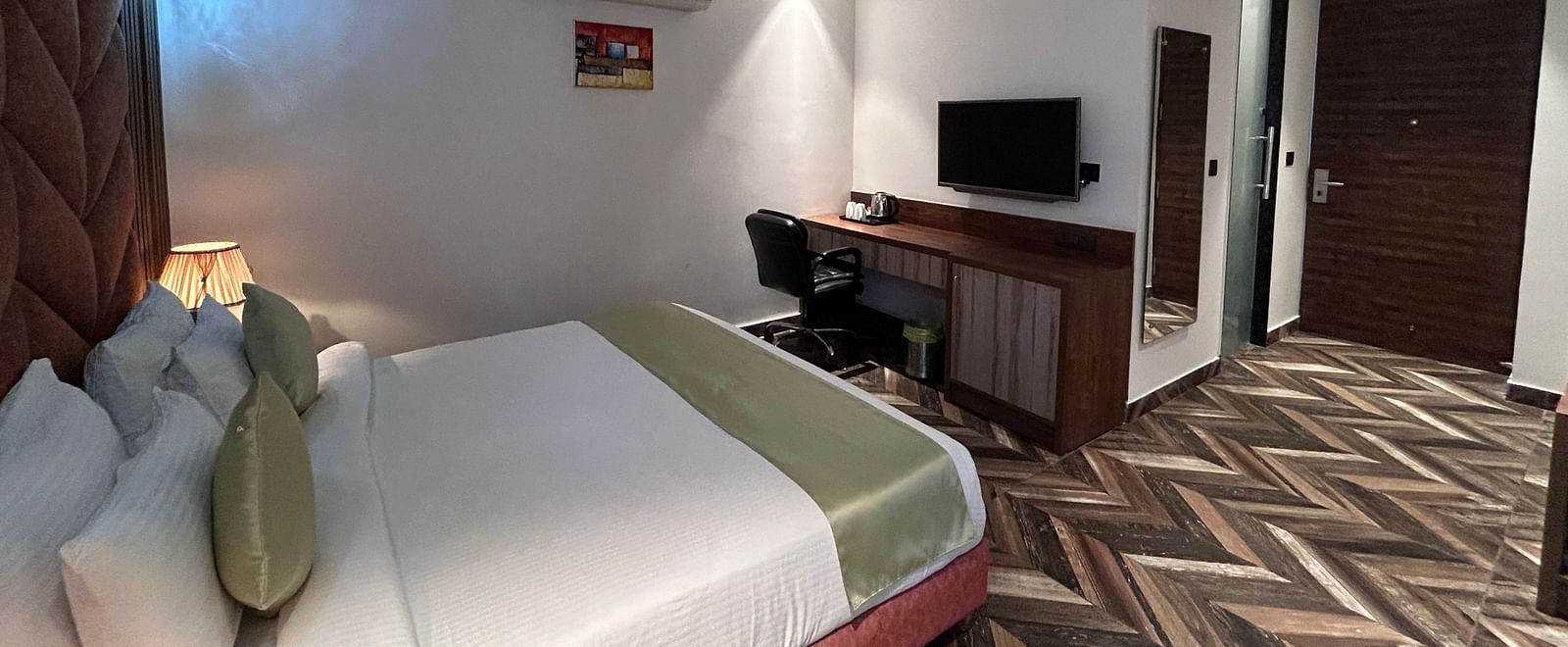 A shot of the premium room showcasing the bed, flat screen TV, ceiling fan, and air-conditioning - DLS Grand Luxotica, Dehradun